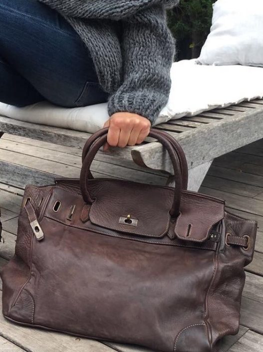 Bolso de piel vintage artesano. Vista lifestyle con modelo portando el bolso en su mano con un look urbano