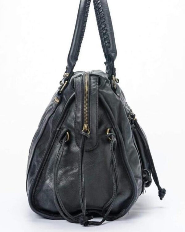 Vista lateral de bolso estilo motorista en piel negra mostrando amplitud, cremalleras y silueta slouchy