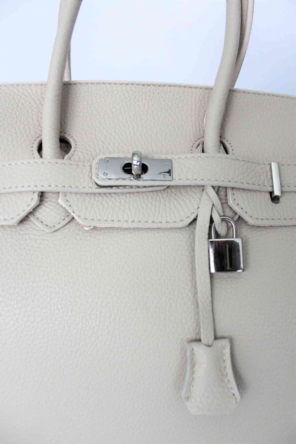 Detalle del cierre con llavero y candado de los bolsos icónicos con candado estructurado color beige