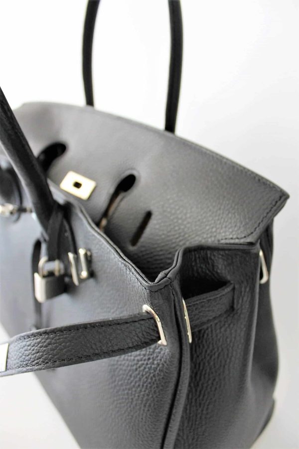 Detalle del bolso negro famoso con candado abierto mostrando las tres solapas del cierre