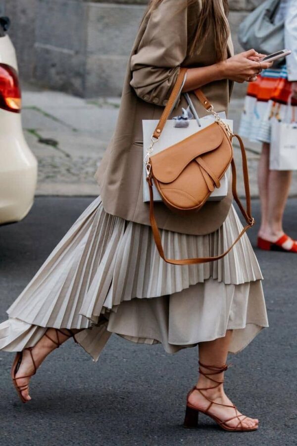 modelo portando el bolso tipo saddle silla de montar color camel con un look arreglado