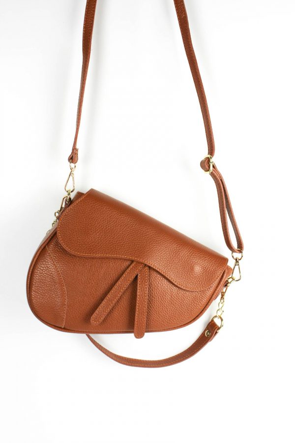 bolso tipo saddle silla de montar color camel, suspendido en el aire por su asa larga extraíble