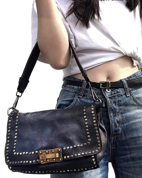 modelo portando el bolso piel lavada vintage negro en su antebrazo con un look urbano