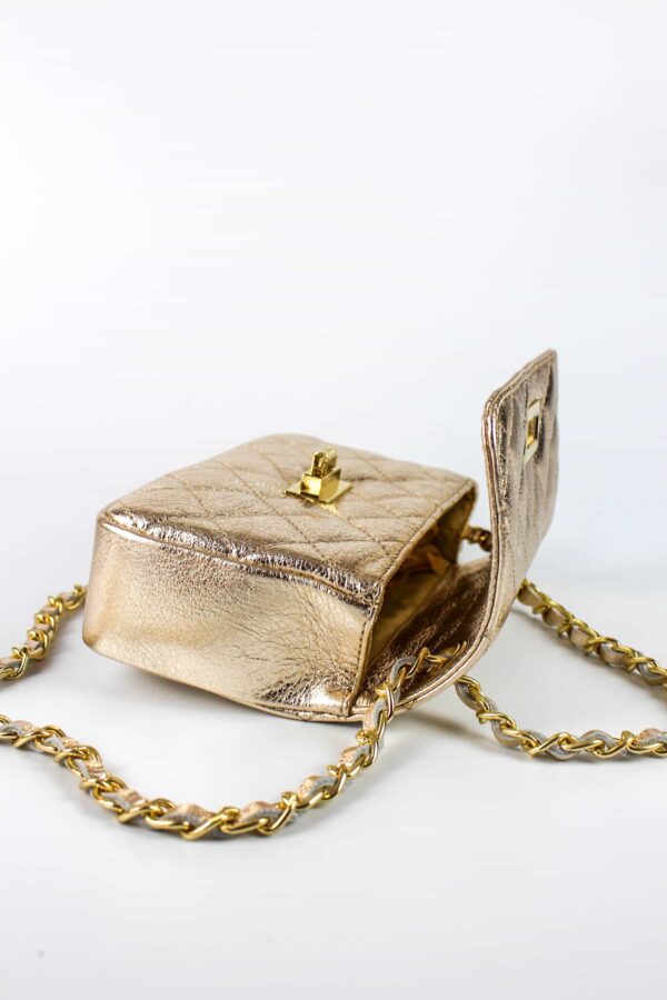 bolso acolchado de piel mini dorado abierto con detalle del cierre dorado giratorio