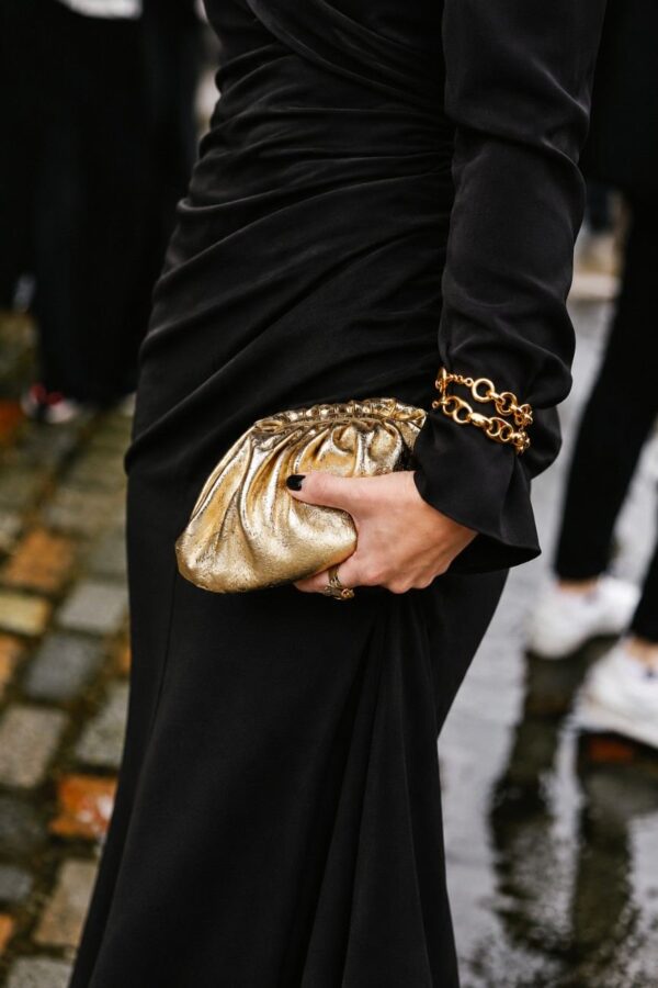 Modelo portando el bolso fruncido piel oro metalizado en su mano con un look de fiesta y evento