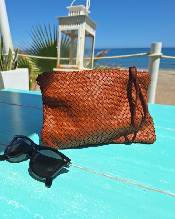 Bolso de mano trenzado vista lifestyle sobre una mesa en la playa