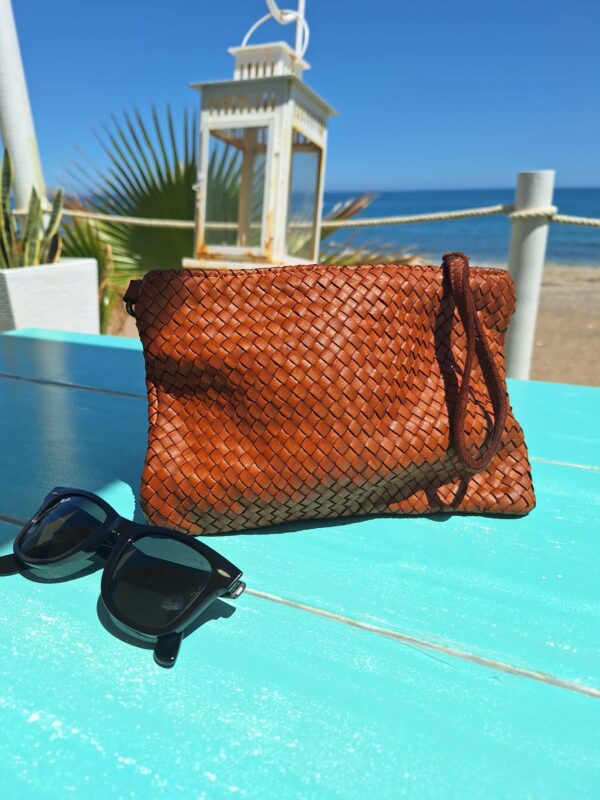 Bolso de mano trenzado vista lifestyle sobre una mesa en la playa