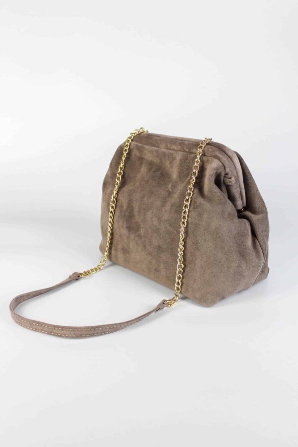 vista lateral del Bolso de ante beige con detalle del asa larga de cadena dorada con refuerzo en el hombro en piel al tono