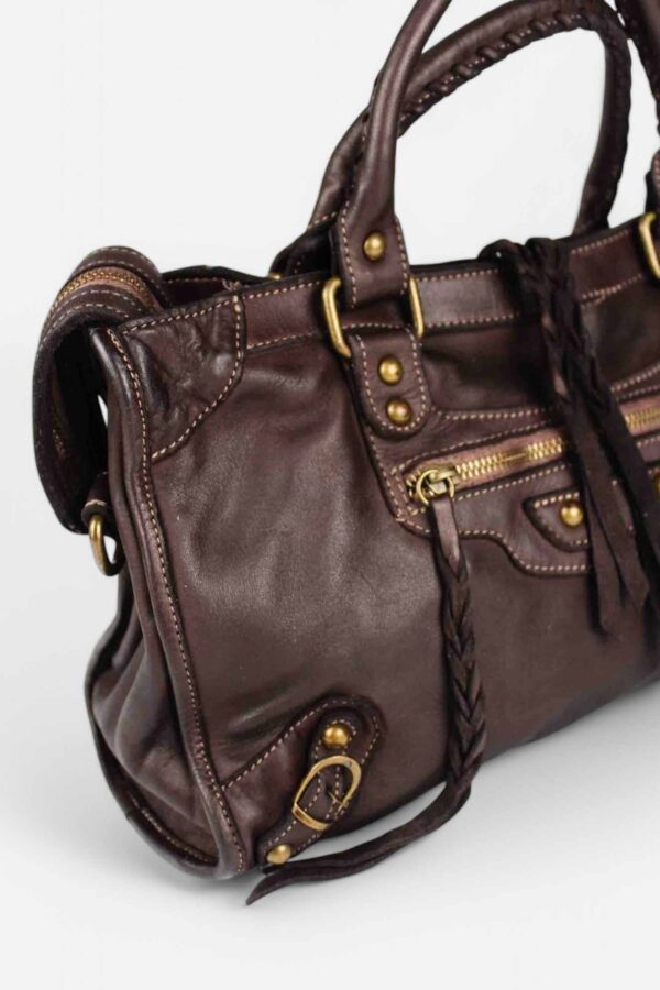 vista lateral con detalle de la cremallera superior y las tachuelas y cordones de piel del bolso city chocolate