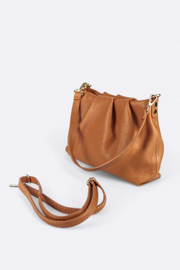 vista lateral del bolso de piel con cierre de frunces colo camel con detalle de las 2 asas extraíbles, una corta para el hombro y otra larga para llevarlo cruzado
