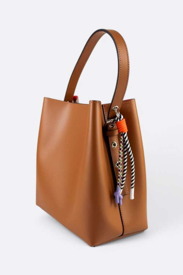 bolso bombonera de hombro de piel. Vista lateral con detalle de charm de nudos