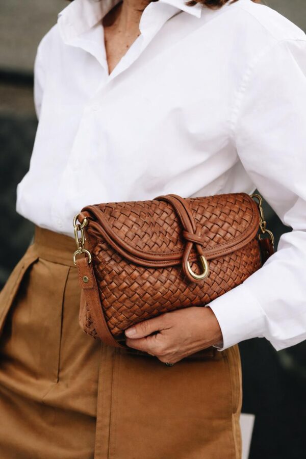 Modelo llevando el bolso camel en la mano con un look arreglado