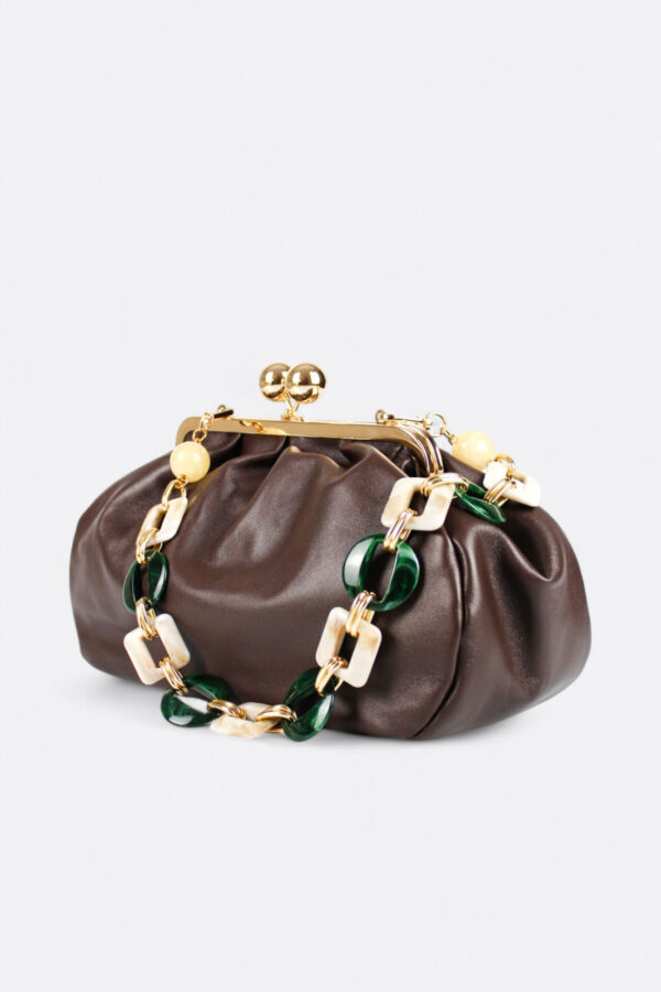 Bolso bombonera de piel marrón chocolate colgado de su asa combinada con eslabones de resina efecto carey y metal dorado, un diseño de clara inspiración italiana