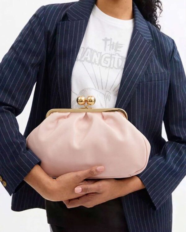 Mujer luciendo el maxi monedero de fin de semana color rosa palo con un look casual