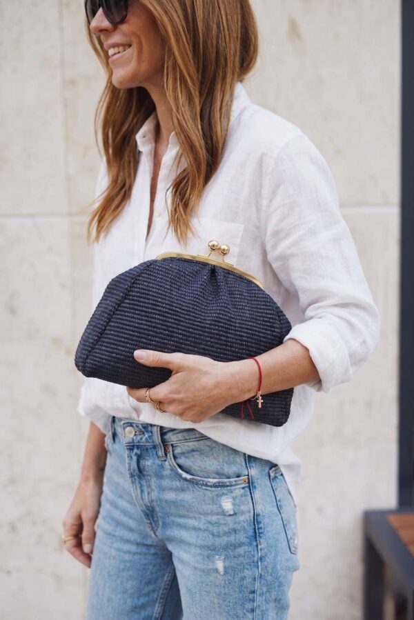 Modelo portando el bolso en su antebrazo con un look urbano de jeans y camisa de lino