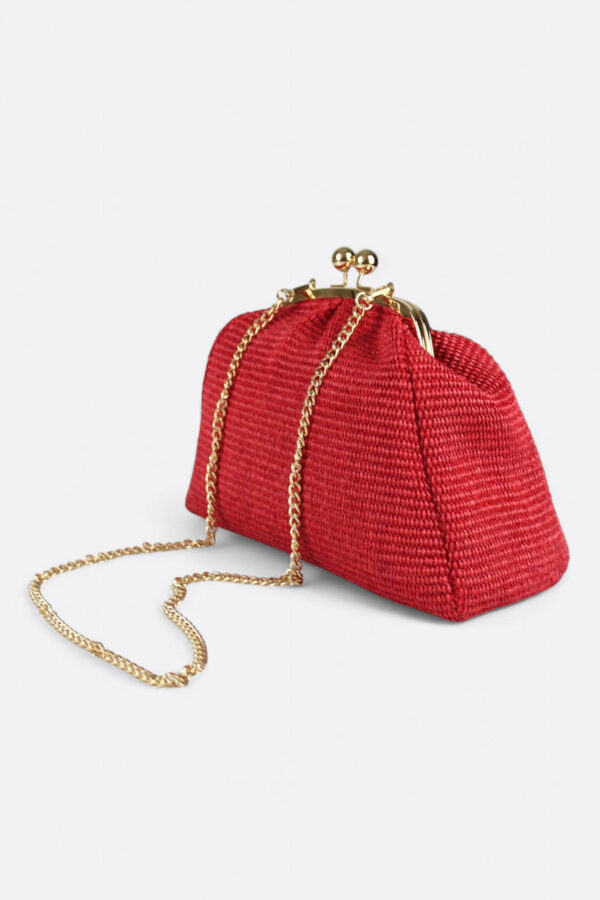 Bolso rojo de rafia con esferas doradas acompañado de su delicada asa de cadena metálica.