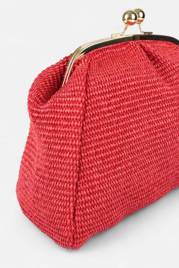 Detalle de la textura premium y el volumen desestructurado del bolso de rafia rojo Monaur Carrie