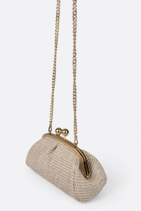 Bolso mini de rafia colgado de su delicada cadena metálica en color beige.