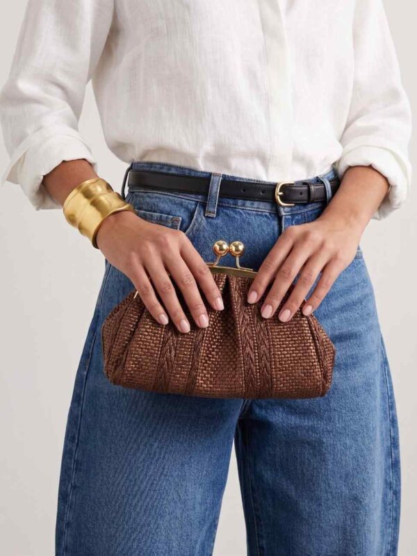 Modelo portando el clutch pequeño de rafia con cierre de bolas marrón chocolate con un look urbano de última tendencia
