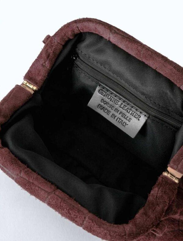 Interior forrado del bolso de ante con cierre de boquilla, mostrando la etiqueta Genuine Leather Made in Italy.