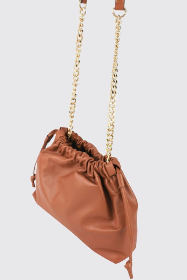 Bolso pouch fruncido color camel colgado por su elegante asa de cadena dorada.