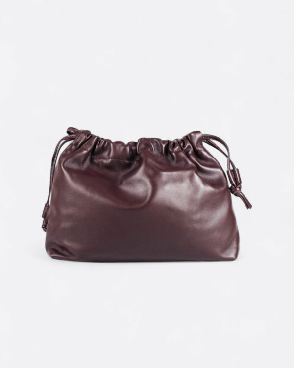 Vista frontal del bolso de piel fruncido marrón chocolate con tiradores de nudo en los laterales.