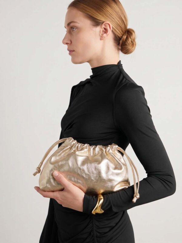 Modelo portando el bolso de fiesta fruncido en piel metalizada dorada con un look de invitada