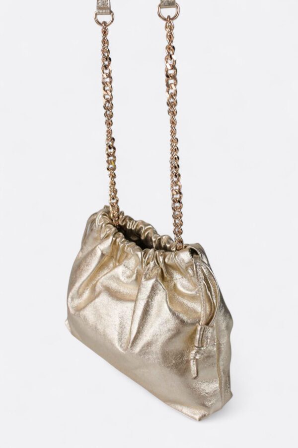 Bolso dorado de piel estilo nube colgado de su asa larga de cadena metálica para eventos.