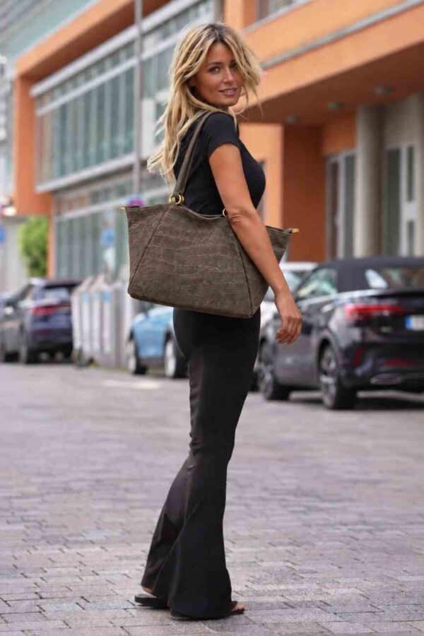 Modelo portando el Bolso XL de ante Arezzo marrón chocolate colgado al hombro con un ourfit de máxima tendencia.